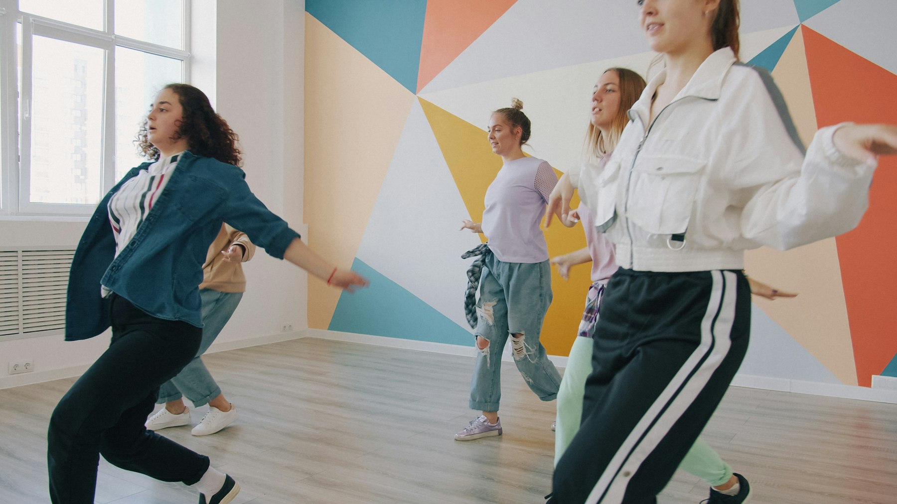 Adult dancers moving together in a bright studio
