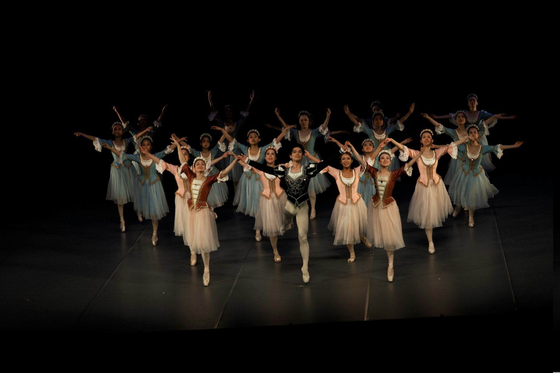A full dance ensemble performing on a theatre stage