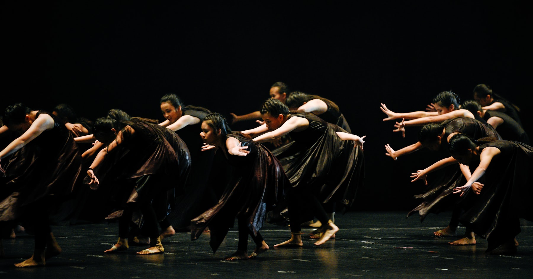 A contemporary dance ensemble performing beneath dramatic stage lights